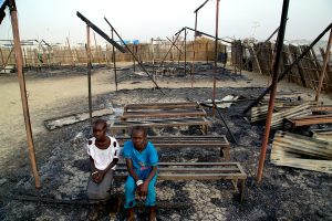 On 3 March 2016 in South Sudan, Chubat (right), 12, sits with her friend in the burned ruins of her school in Malakal Protection of Civilian site. The UNICEF supported primary school was burnt down in fighting on 17-18 February 2016, that left at least 18 people dead. Chubat and her friend used go to the school every day and enjoyed learning new things, especially during their English and math classes. 470 children attended grades 1 through 6. The school had five classrooms and seven teachers who taught English, Social Science, Christian Religious Education, and Mathematics. Due to the lack of space in the PoC, the same classrooms were used for CFS activities in the afternoon. In 2016, UNICEF launched the second phase of the Back to Learning initiative, targeting almost 600,000 children across the country. South Sudan has one of the largest number of children not attending school in the world.