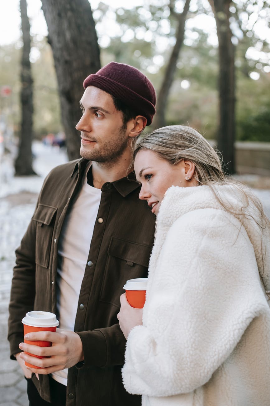young man with girlfriend drinking coffee in park