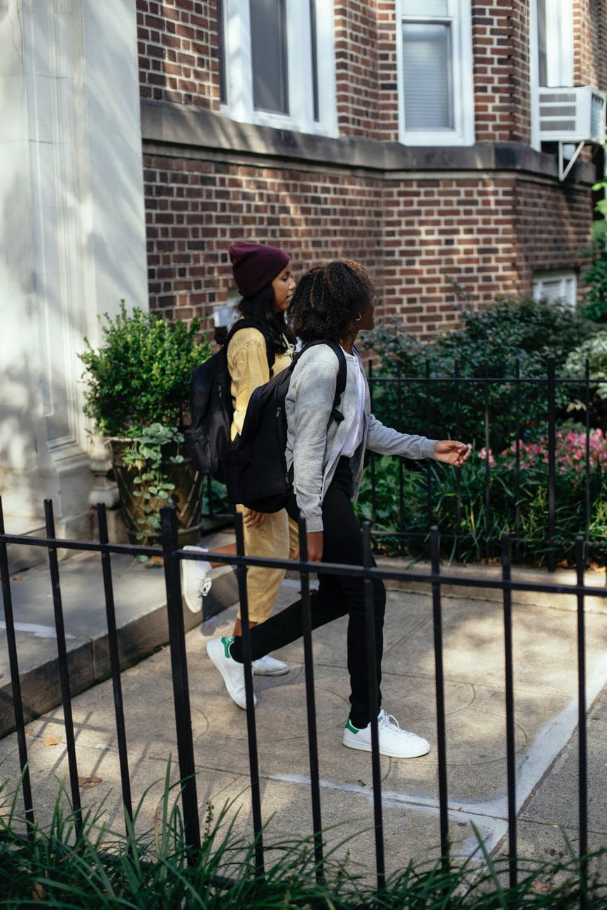 multiracial girls walking on stairs near brick building