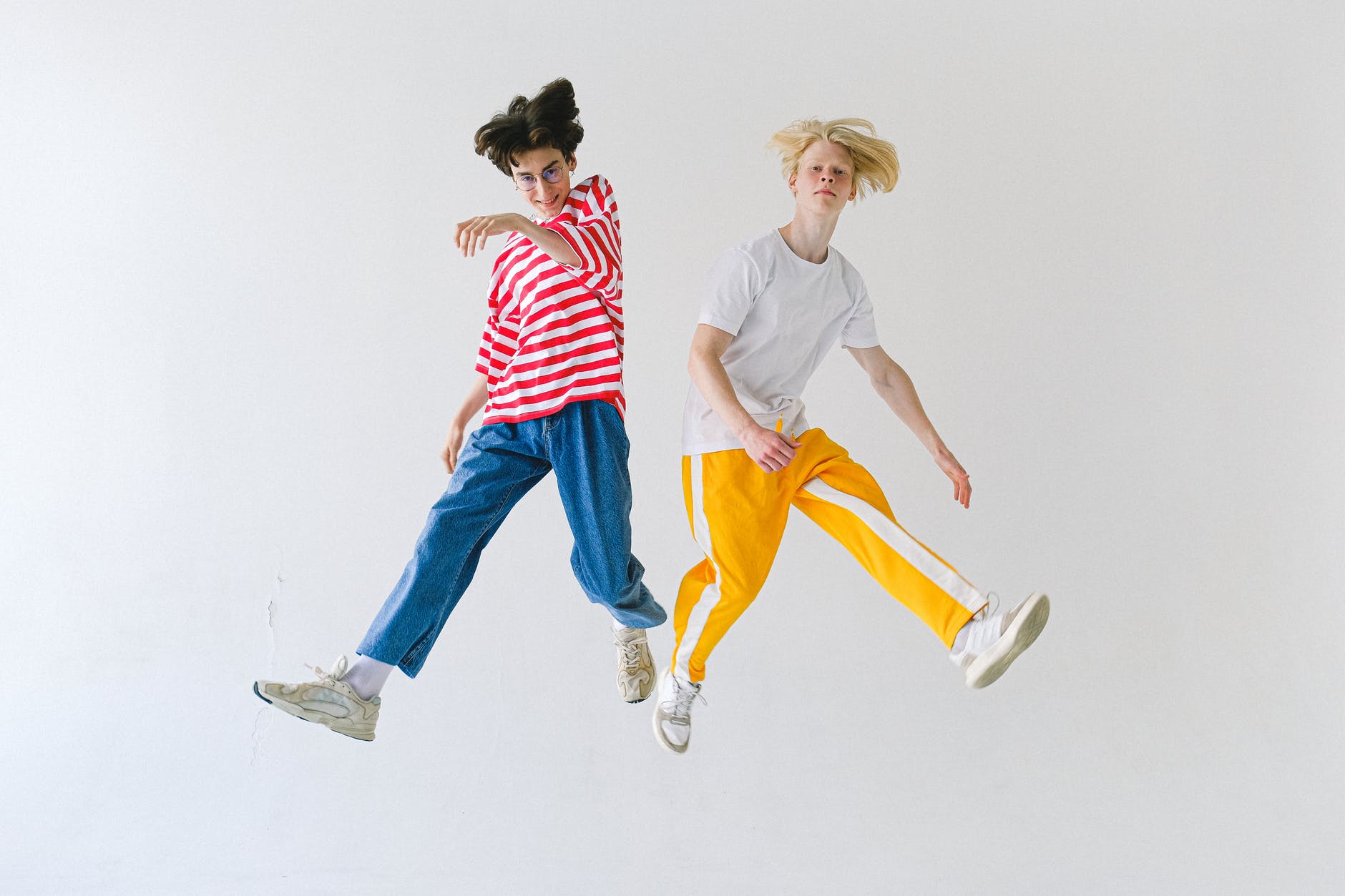 cheerful friends jumping above floor and looking at camera