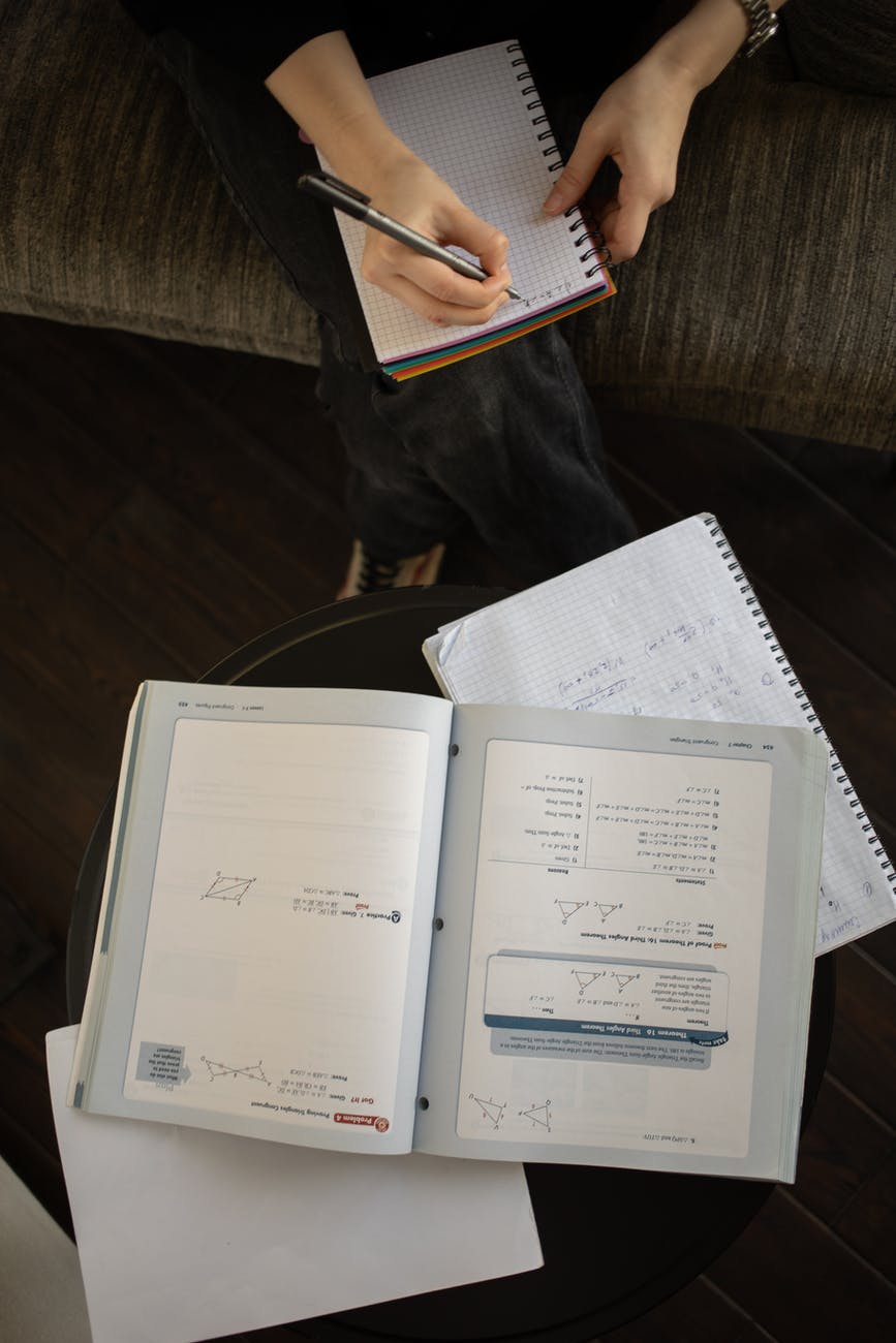 crop unrecognizable person writing in notepad and doing paperwork
